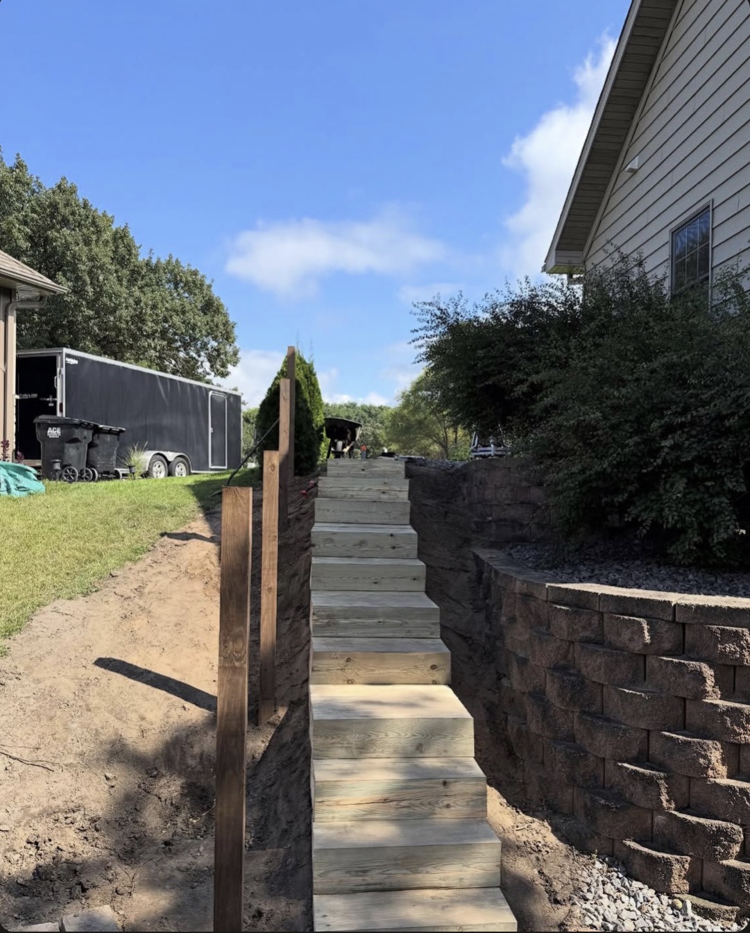 Custom wood stairway alongside boulder retaining wall in Central Minnesota